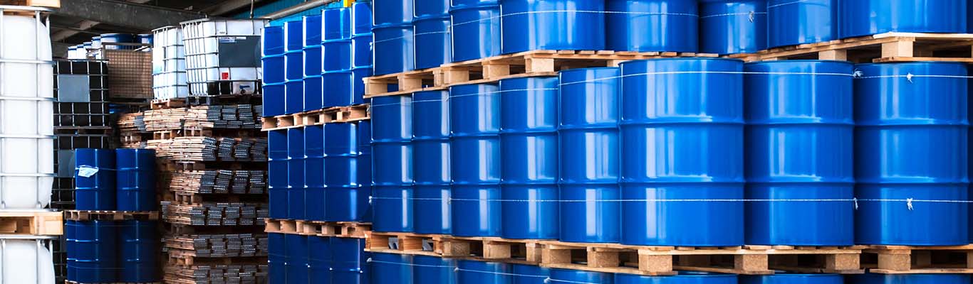 3 tiers of blue chemical drums sit on palettes in a warehouse