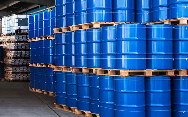 3 tiers of blue chemical drums sit on palettes in a warehouse