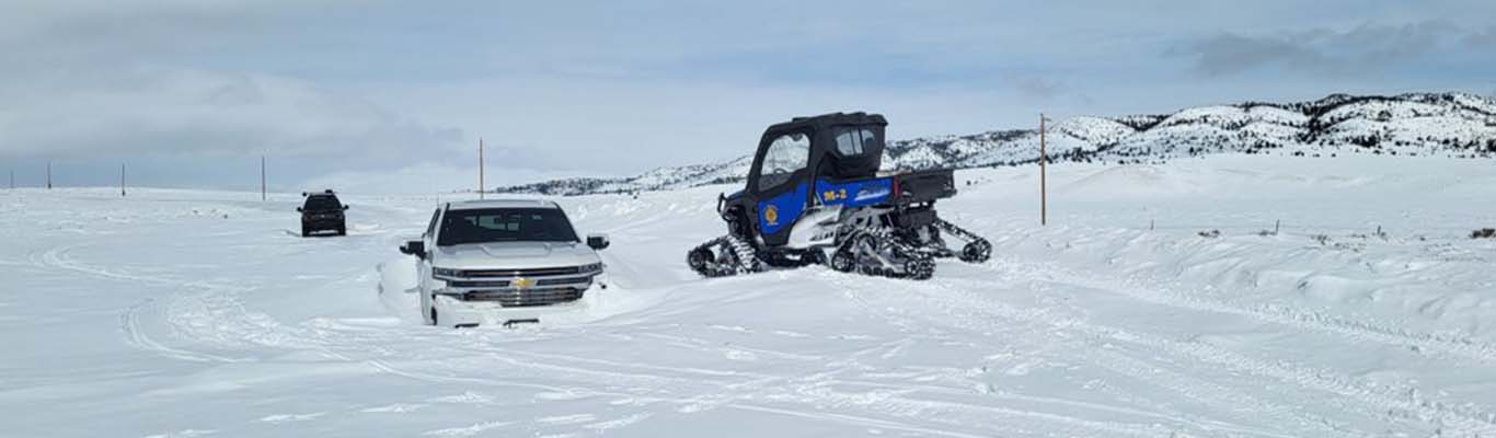 vehicle stuck in the snow with a rescue vehicle helping