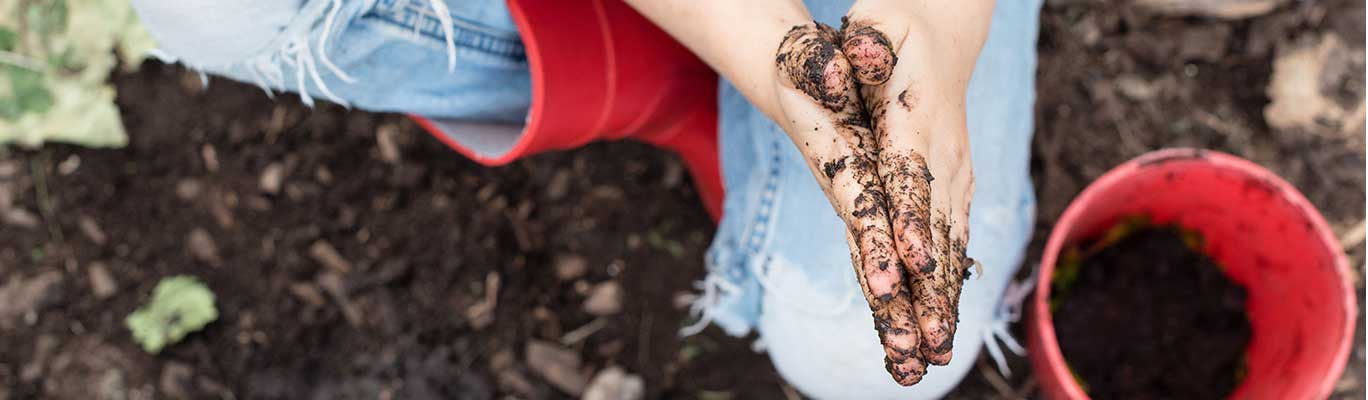 Child playing in dirt with red bucket