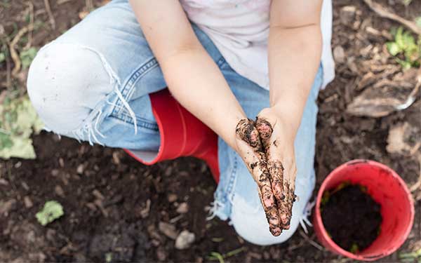 Child playing in dirt with red bucket