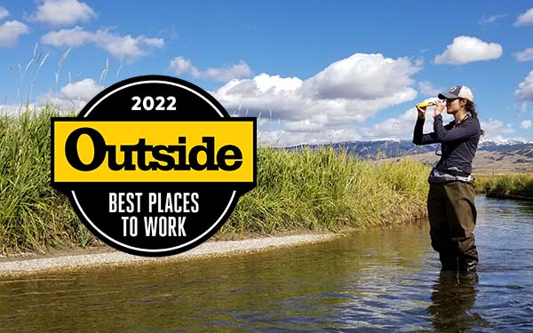 Woman in creek with Outside Magazine award emblem