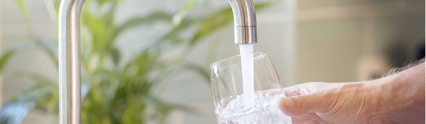 Faucet water filling a clear glass