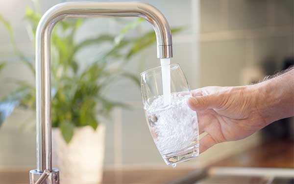 Faucet water filling a clear glass